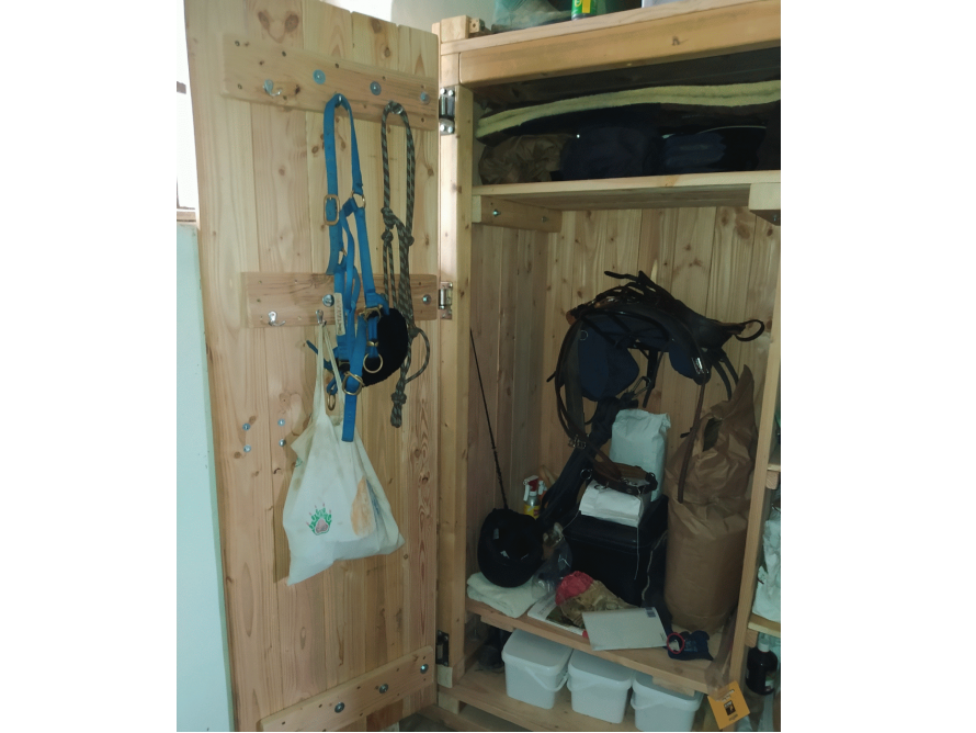 Offener Holzschrank mit Reitzubehör