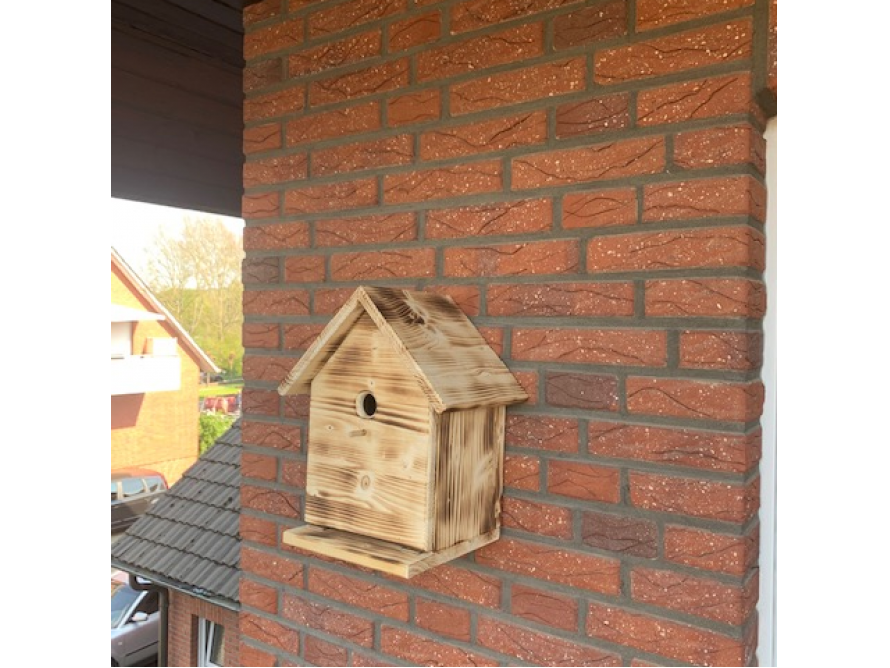 Vogelnistkasten aus Holz an Backsteinwand