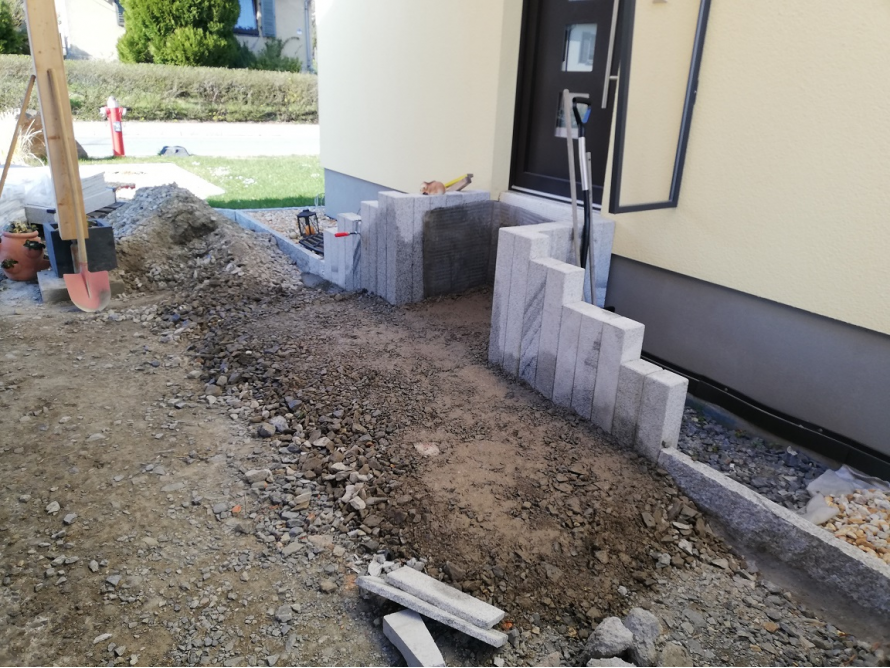 Pflasterarbeiten mit Granitsteinen und Schaufel