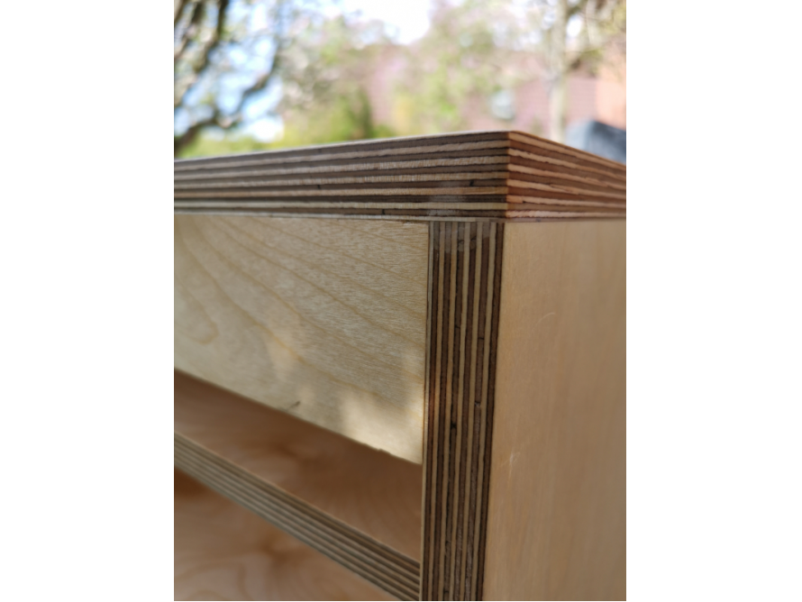 Nahaufnahme: Ecke eines Möbelstücks aus hellem Holz.