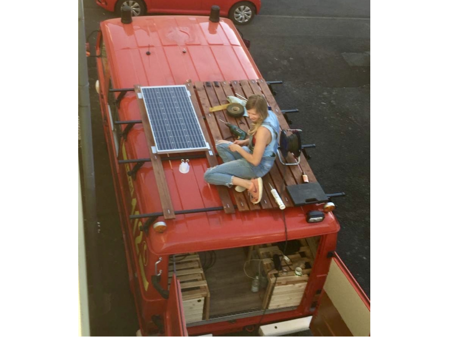 Person montiert Solarpanel auf Transporterdach