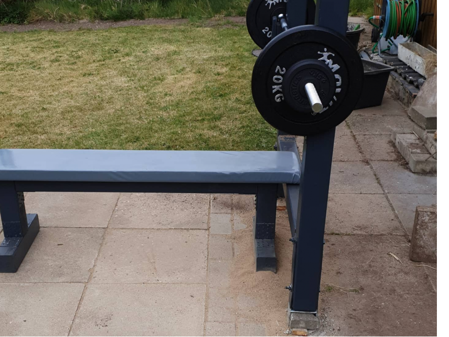 Eine Hantelbank mit einer Langhantel im Garten.