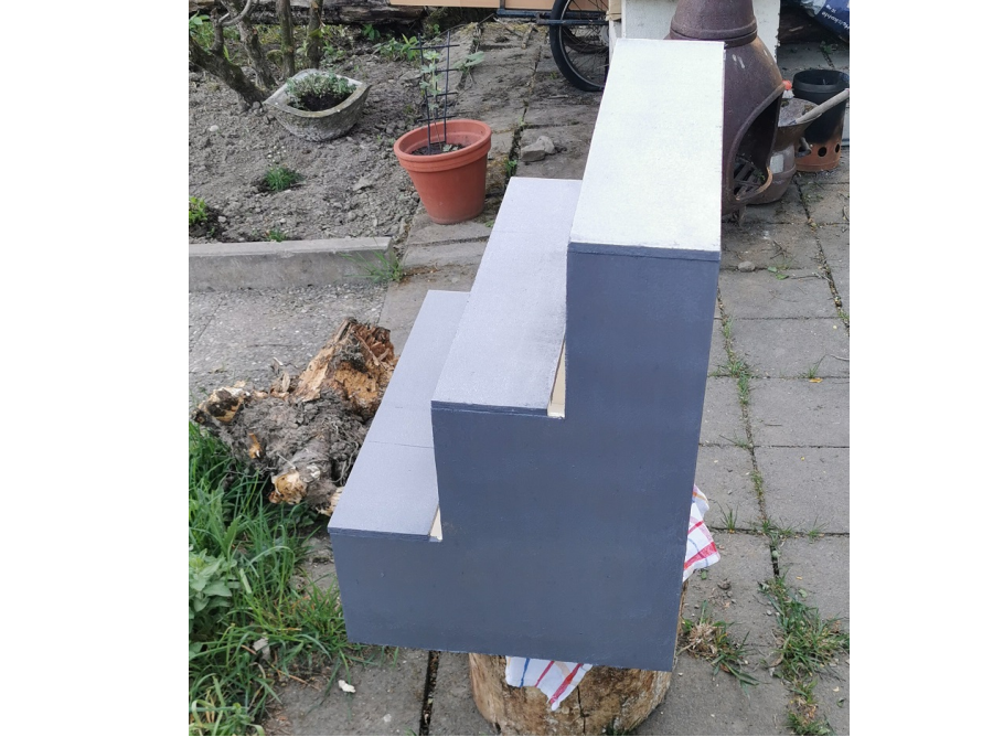 Eine dreistufige Holztreppe in grau.