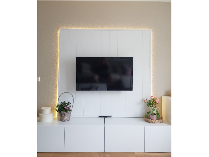 Ein Fernsehgerät an einer weißen Wand mit Beleuchtung.