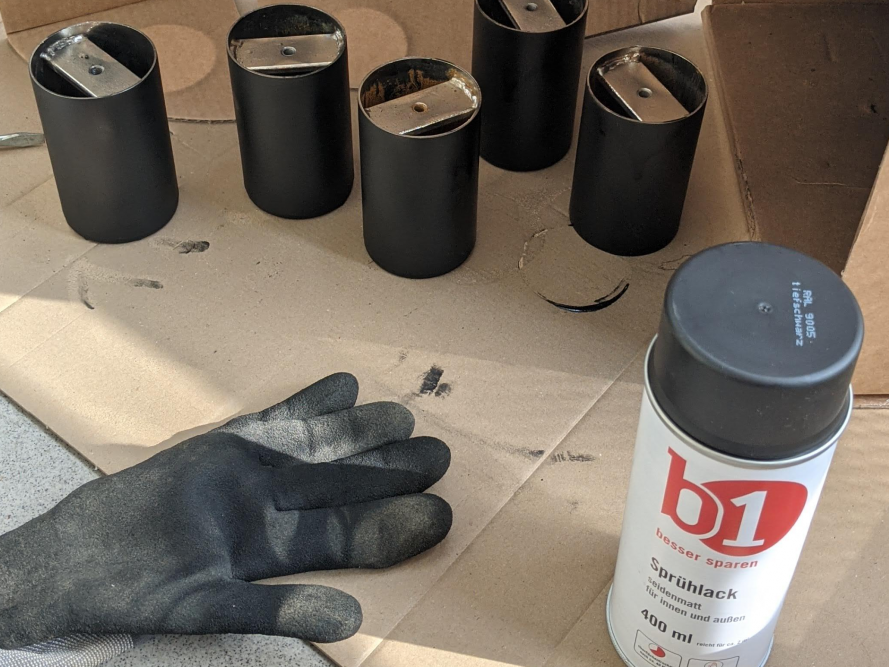 Mehrere schwarze Sprühdosen und ein Handschuh