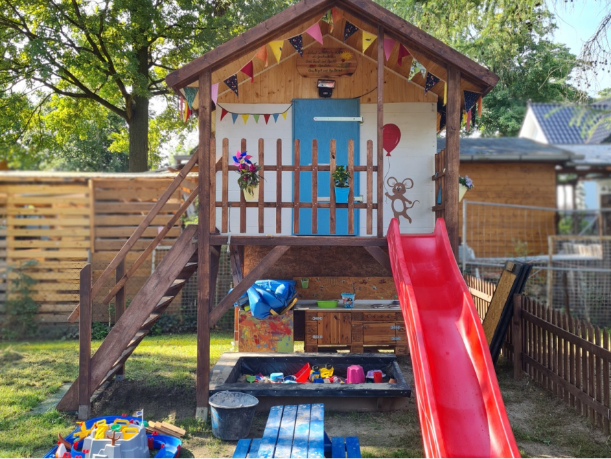 Hölzernes Spielhaus mit Rutsche und Sandkasten