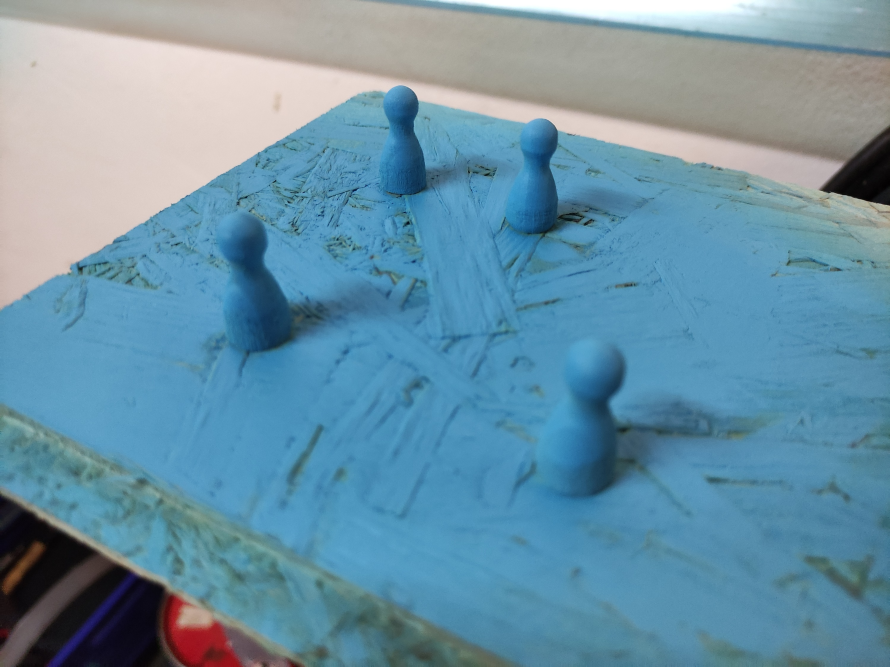 Vier blaue Spielfiguren auf blauer Fläche