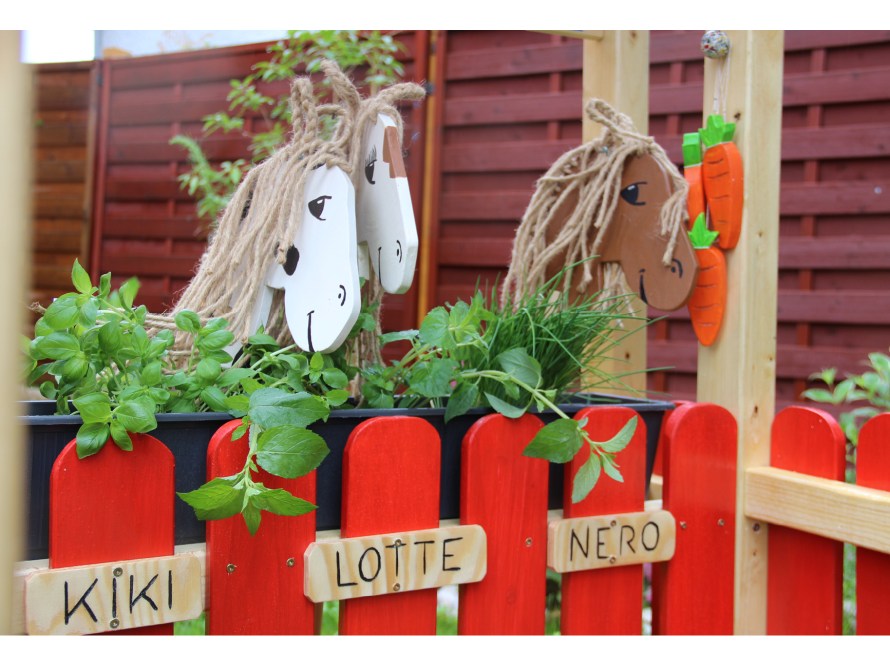 Holzpferde und Kräuter in einem Hochbeet