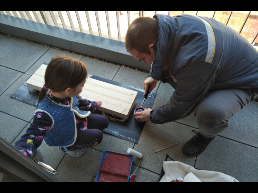 Person und Kind beim Lasieren von Holz