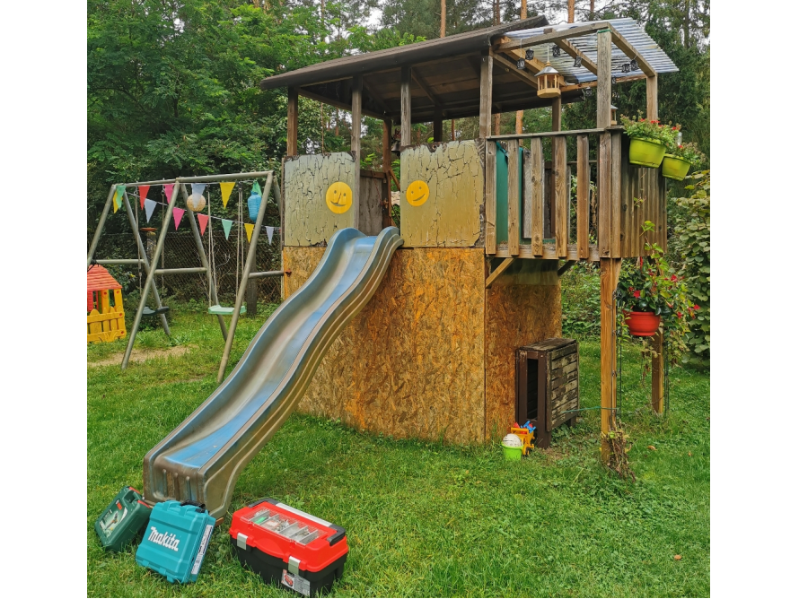 Ein Spielplatz im Garten mit Rutsche und Schaukel