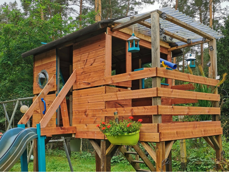 Ein Baumhaus aus Holz mit blauer Rutsche