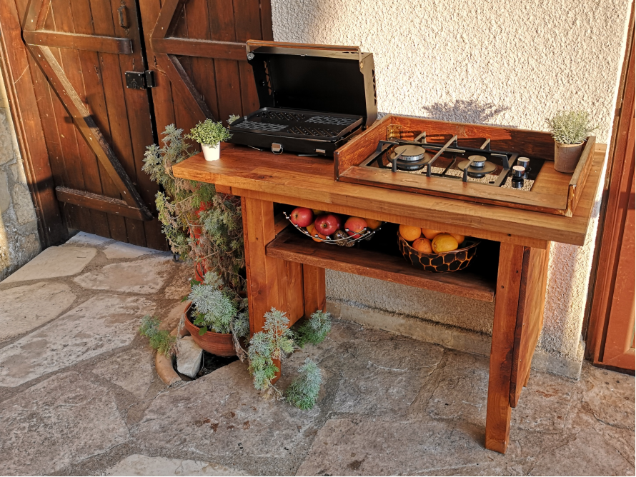 Außenküche aus Holz mit Grill und Kochstelle