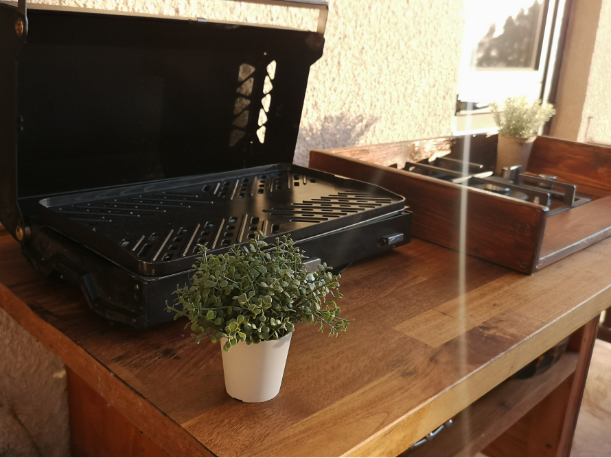 Ein geöffneter Grill und ein Gaskocher auf einem Holztisch.
