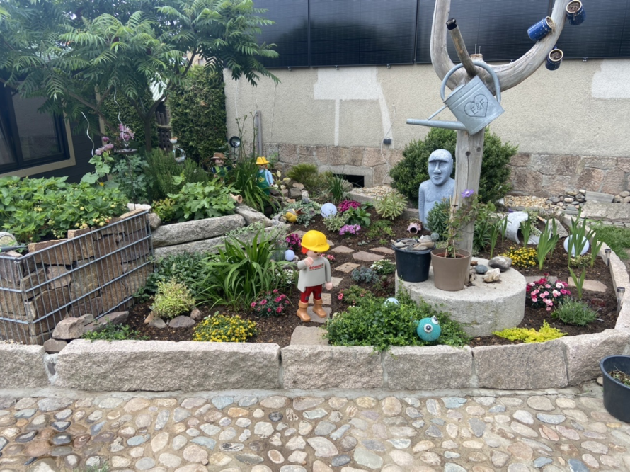 Bunter Garten mit Figuren und Steinen