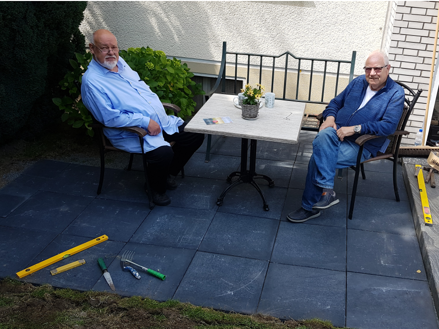 Zwei Personen sitzen an einem Tisch im Garten