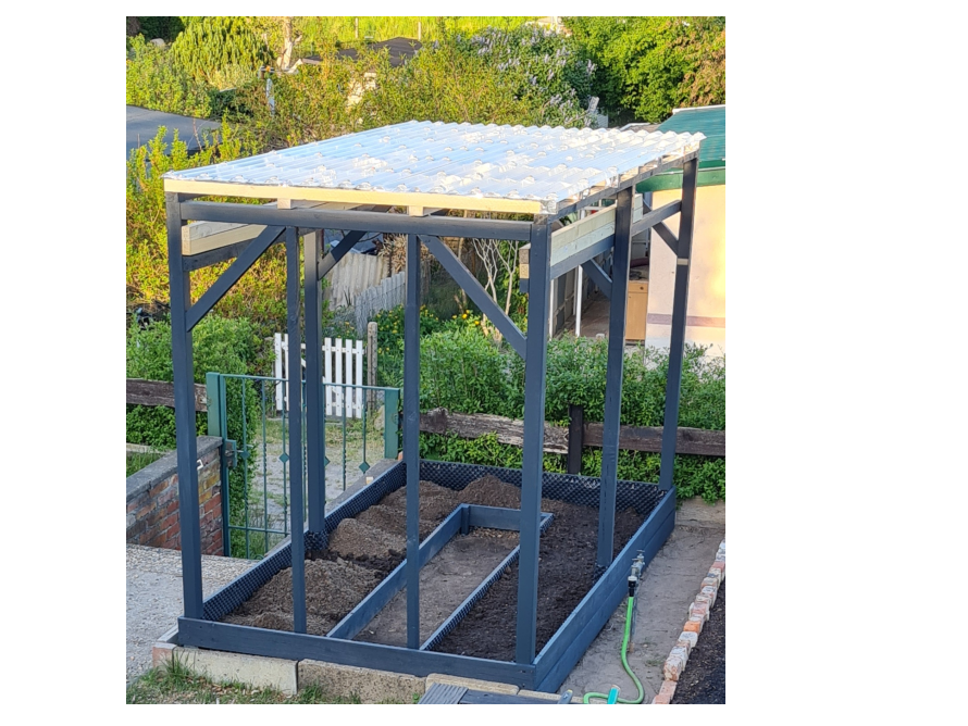 Holzgerüst mit Foliendach über einem Hochbeet