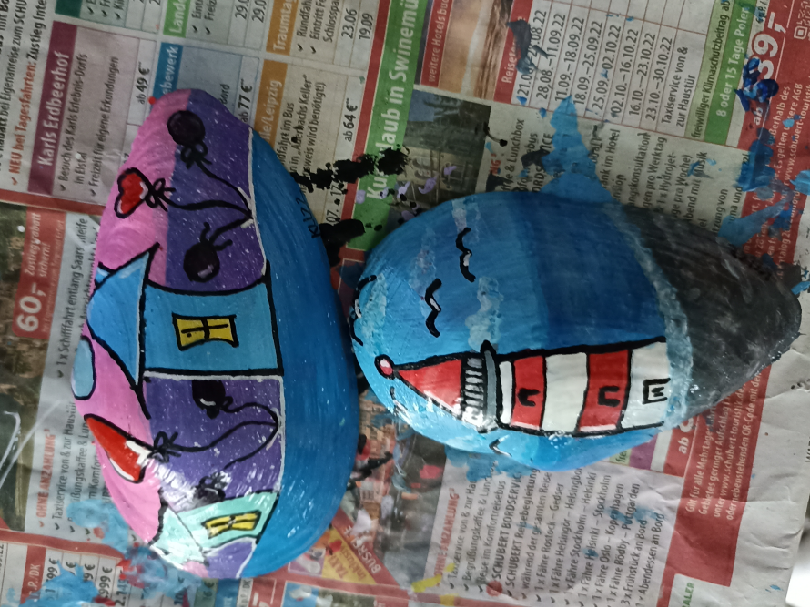 Zwei bemalte Steine: ein Haus und ein Leuchtturm