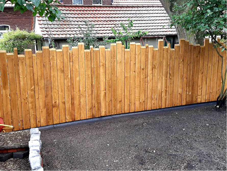 Hölzerner Gartenzaun mit unregelmäßiger Höhe.