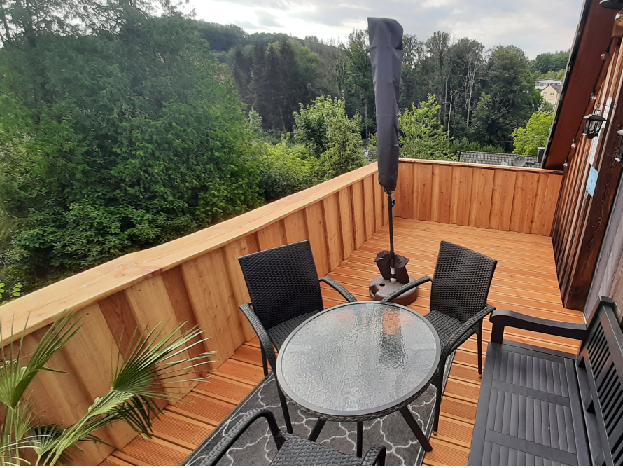 Holzterrasse mit Gartenmöbeln und Sonnenschirm