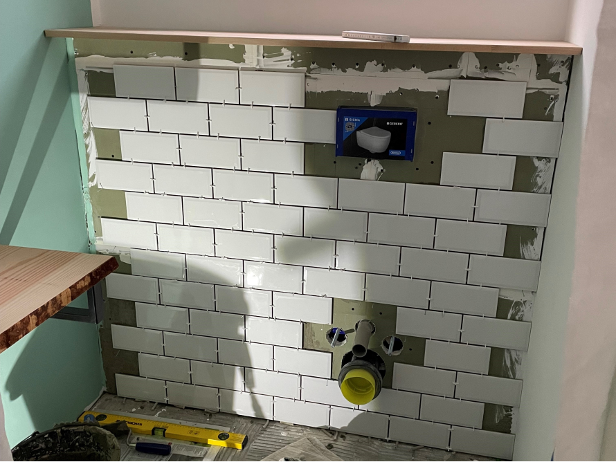 Verfliesen einer Badezimmerwand mit weißen Fliesen