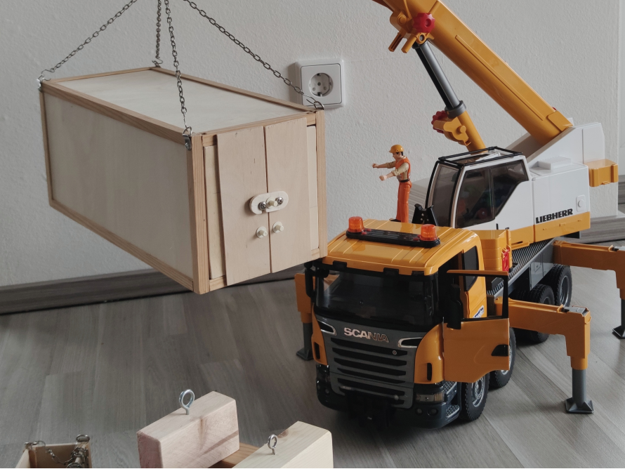 Spielzeugkran hebt Holzkiste