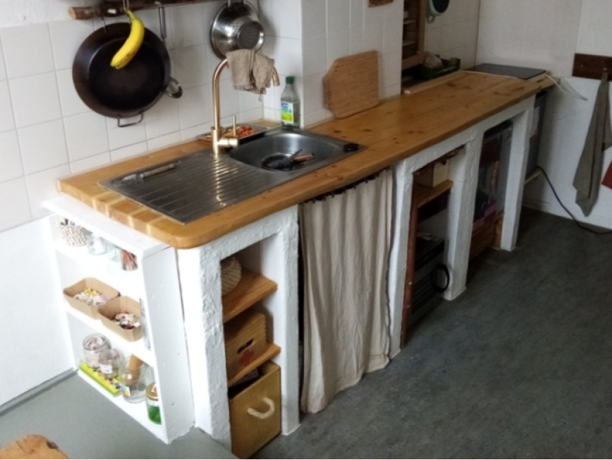 Selbstgebaute Küche mit Holzarbeitsplatte und weißen Schränken