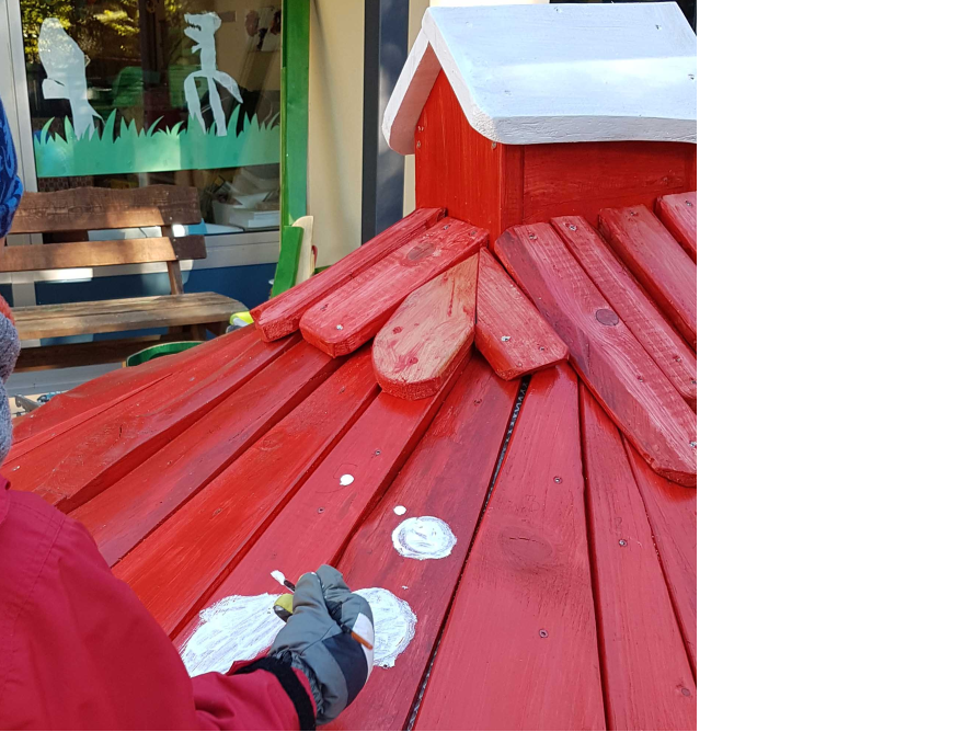 Person streicht rotes Holzdach weiß an