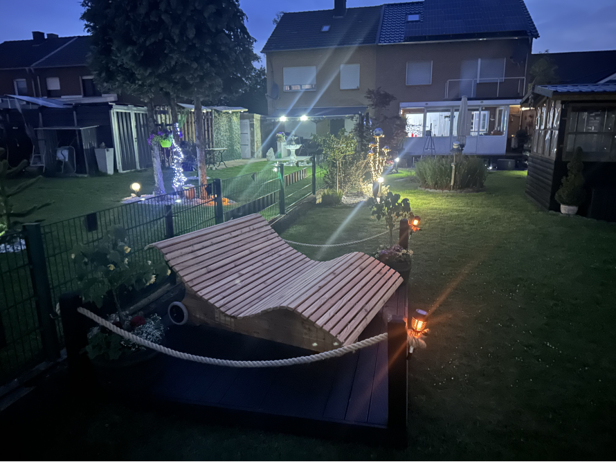 Holzliege im beleuchteten Garten