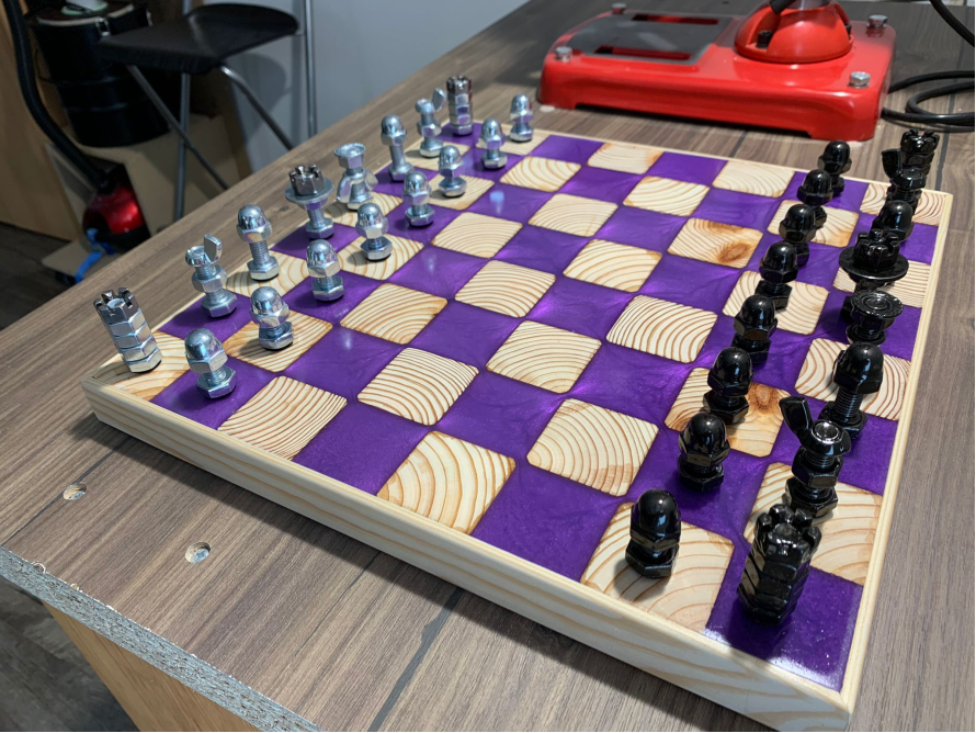 Schachbrett aus Holz mit Muttern und Schrauben als Figuren