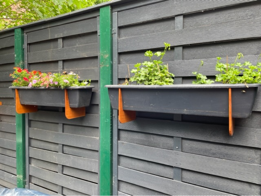 Zwei Blumenkästen an einem Zaun