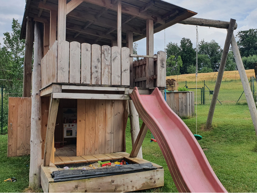 Hölzerner Spielturm mit Rutsche und Schaukel
