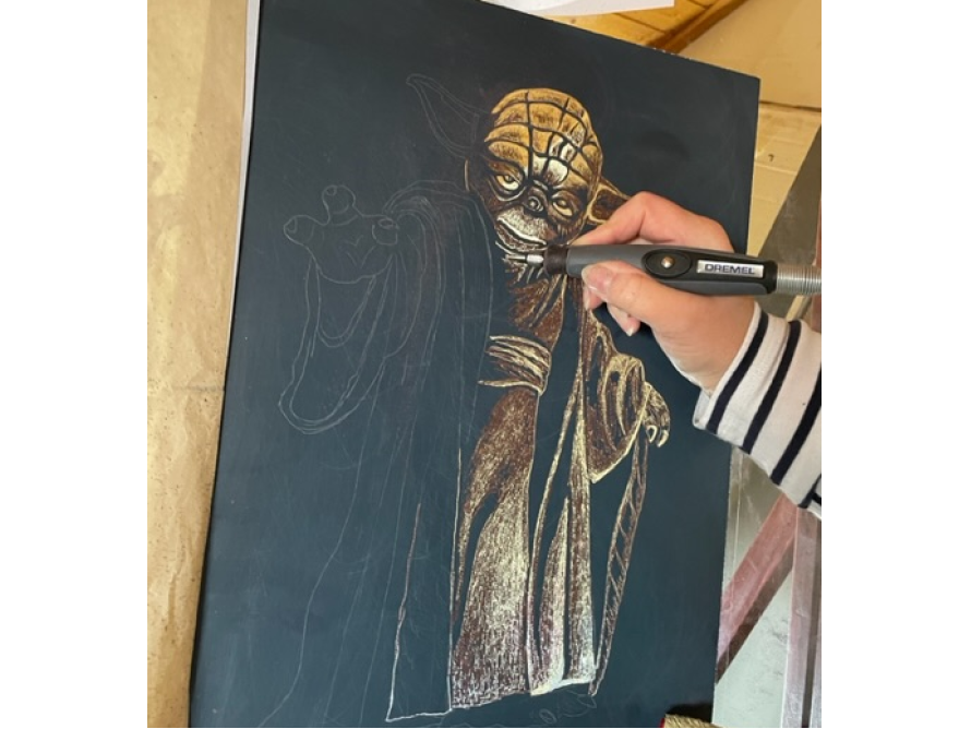 Person graviert eine Zeichnung mit einem Gravierwerkzeug