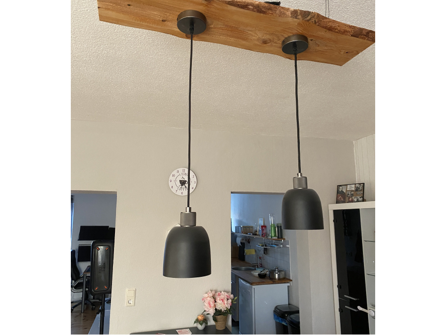 Zwei schwarze Hängelampen an Holzbalken