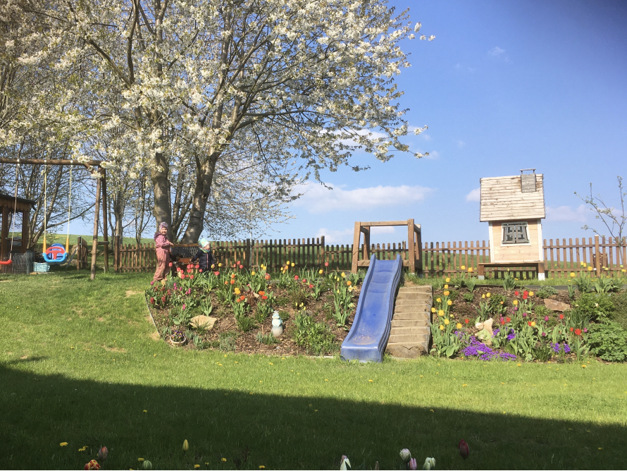 Garten mit Spielplatz und blühenden Bäumen