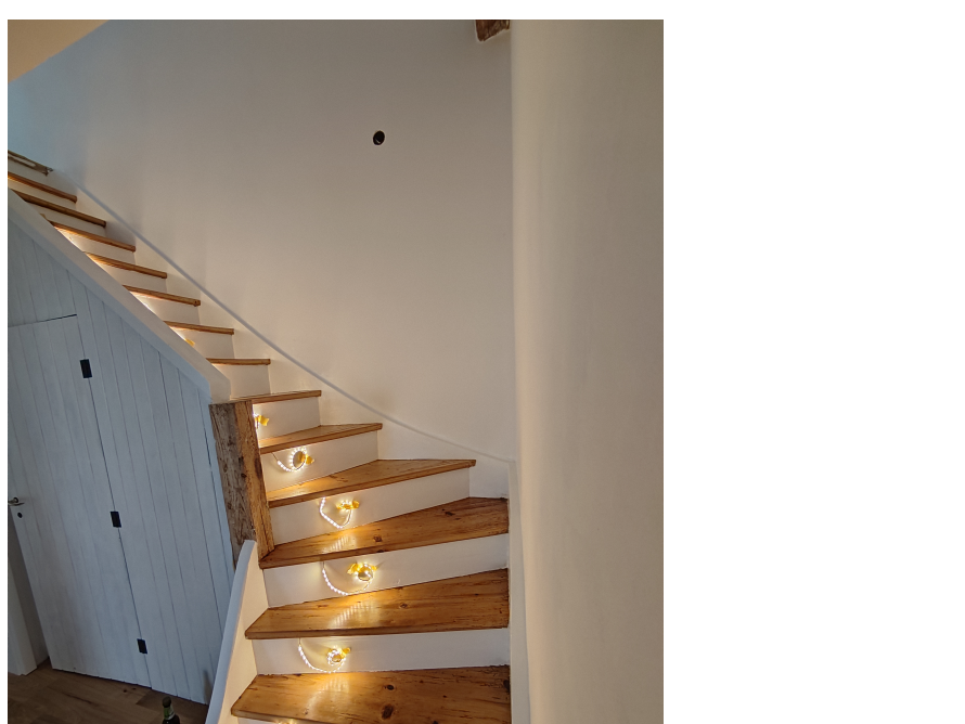 Beleuchtete Holztreppe mit weißem Geländer