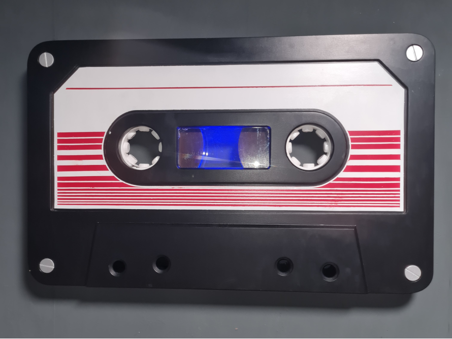 Eine schwarze Audiokassette mit rot-weißen Streifen.