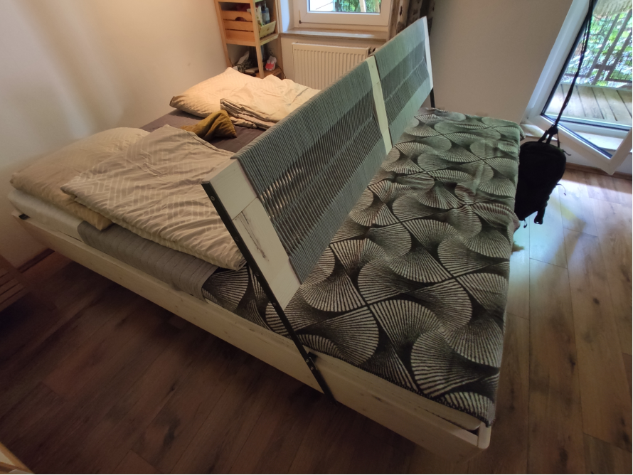 Doppelbett mit Holzrahmen und gemusterter Tagesdecke