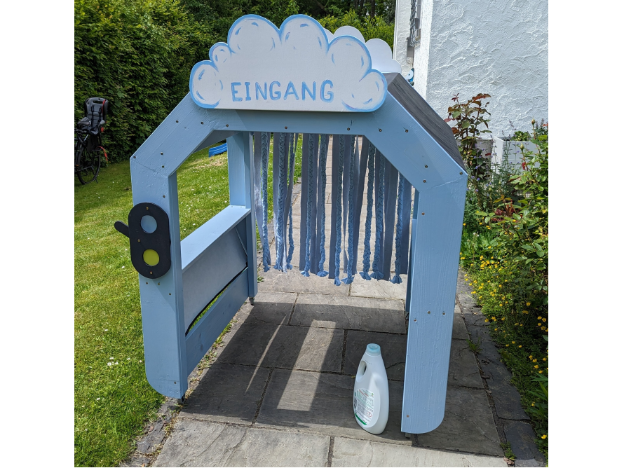 Blaues Spielhaus mit Stoffstreifen