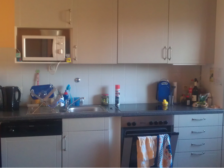 Eine einfache Küche mit grauen Schränken und Elektrogeräten.