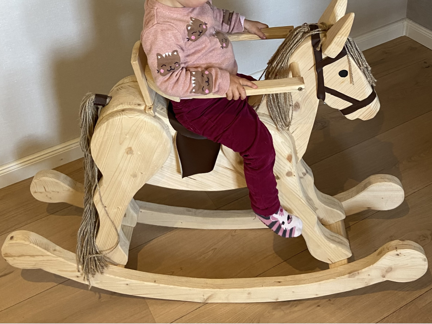 Kleinkind auf einem Schaukelpferd aus Holz