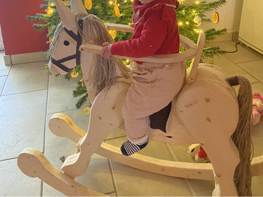 Kleinkind auf einem Schaukelpferd aus Holz