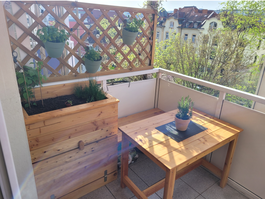 Sonniger Balkon mit Holzmöbeln und Pflanzen