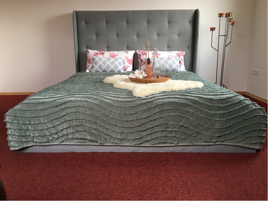 Gemachtes Bett mit grauem Kopfteil