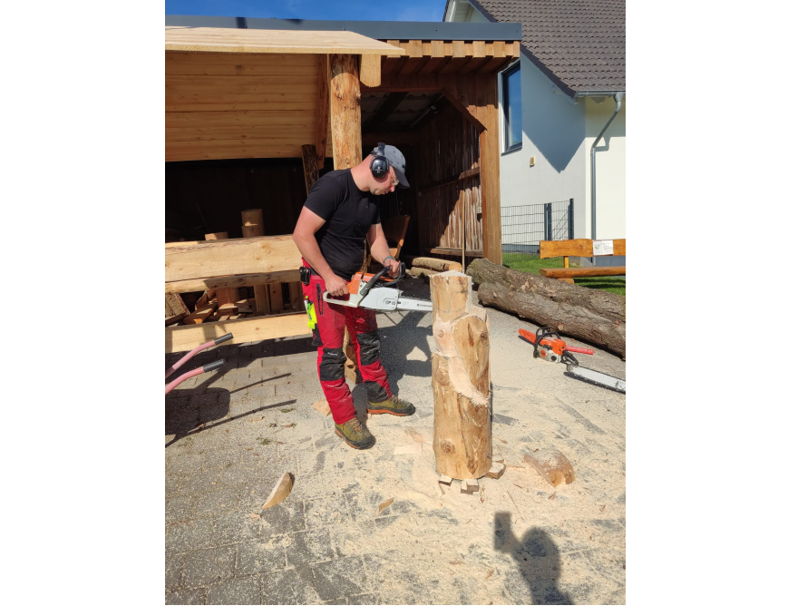 Person schnitzt mit Kettensäge eine Holzskulptur