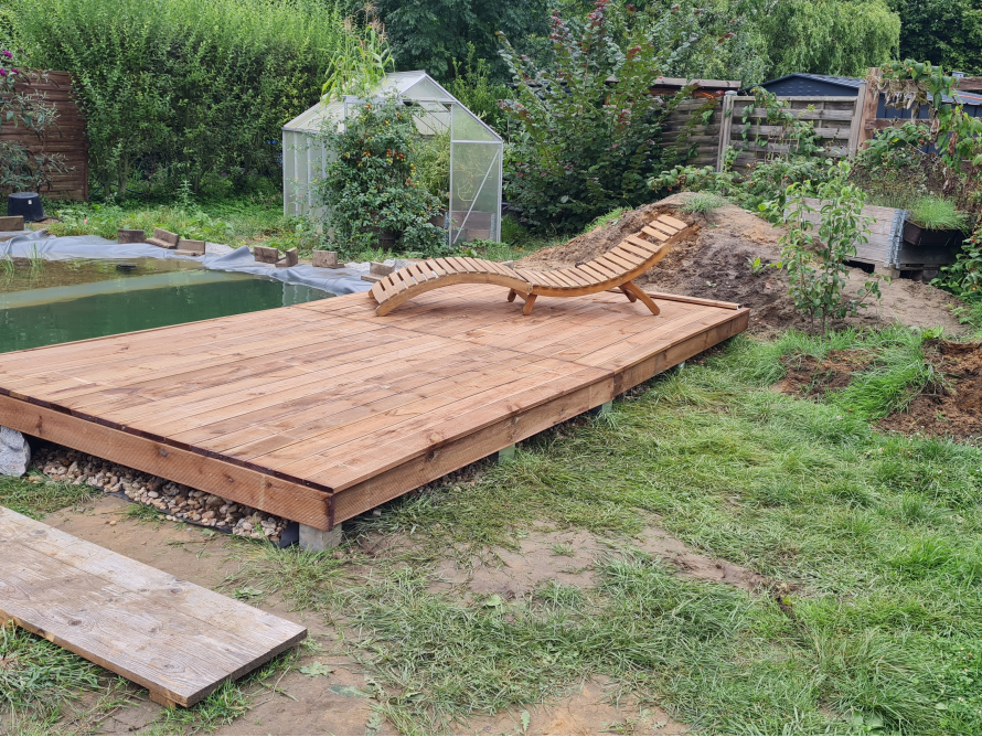 Holzterrasse am Gartenteich mit Liege