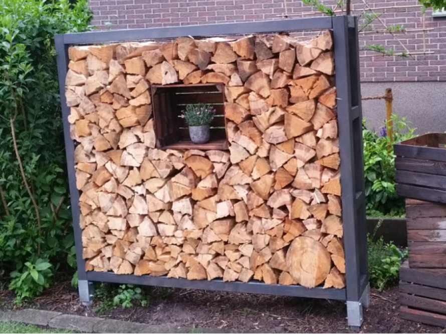 Holzstapel mit Pflanze in einem Metallgestell