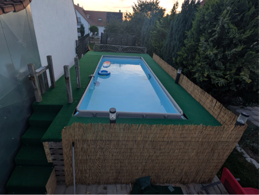 Rechteckiger Pool im Garten mit Kunstrasen und Schilfmatte