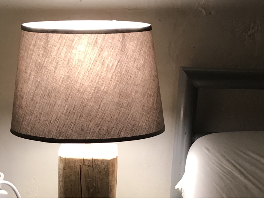Eine Lampe mit einem Lampenschirm aus Stoff auf einem Holzsockel