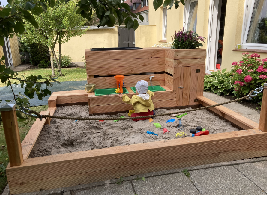 Kind in einem Sandkasten aus Holz
