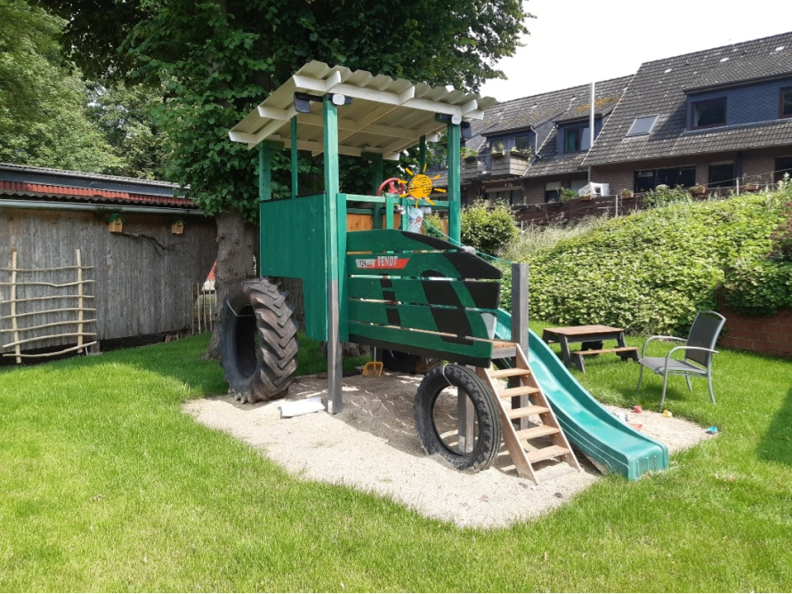 Spielhaus in Form eines Traktors mit Rutsche